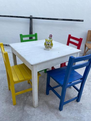 a white table with colorful chairs and a vase on it at Vive Alegria Hostel in Puerto Vallarta