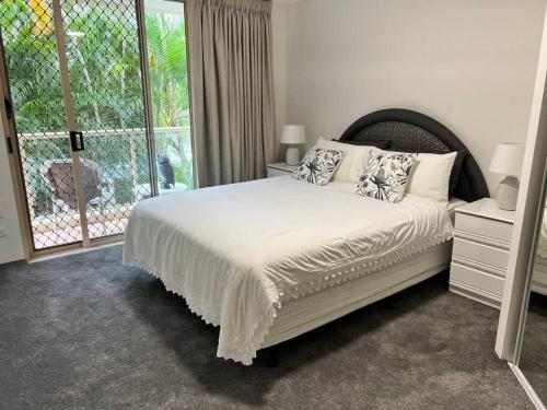 a bedroom with a bed and a large window at Santa Monica Apartments - Hosted by Burleigh Letting in Gold Coast