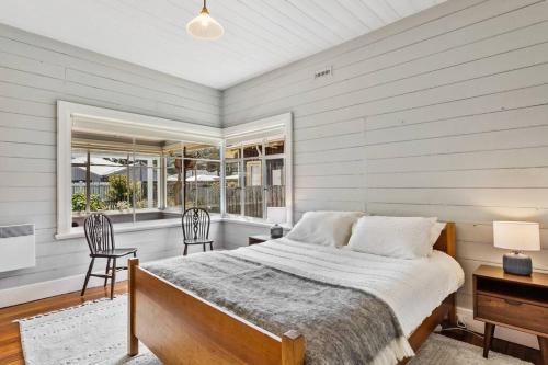 a bedroom with a bed and two chairs and a window at 'Balmoral Cottage' A Kingston Beach Escape in Kingston Beach