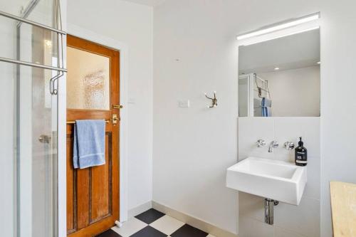 a white bathroom with a sink and a mirror at 'Balmoral Cottage' A Kingston Beach Escape in Kingston Beach