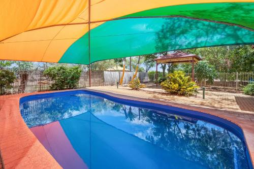 a rainbow colored umbrella over a swimming pool at Outback Caravan Park Tennant Creek in Tennant Creek