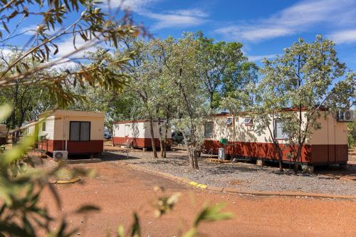 a group of three mobile homes parked in a field at Outback Caravan Park Tennant Creek in Tennant Creek