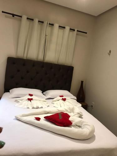 a bed with white sheets and red roses on it at Pousada Rekantu do Poeta in Alter do Chao