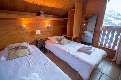 a bedroom with two beds in a log cabin at Chalet Clearmount with Spa in Méribel