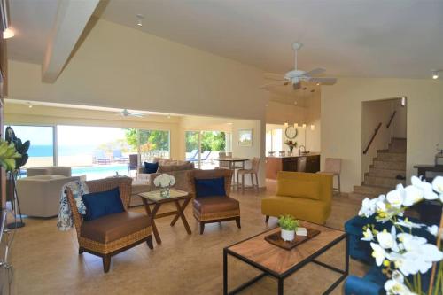 ein Wohnzimmer mit Sofas, Stühlen und einem Tisch in der Unterkunft Villa Zircon in Pelican Key awaits you in Koolbaai