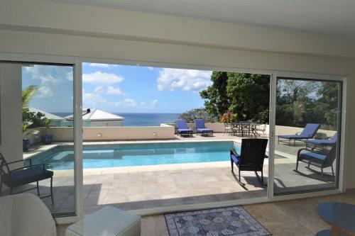 einen Pool mit Stühlen und Meerblick in der Unterkunft Villa Zircon in Pelican Key awaits you in Koolbaai
