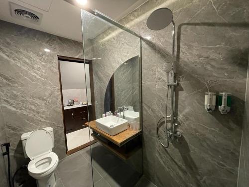 a bathroom with a toilet and a sink and a shower at Ohana Suites Yogyakarta in Ngabean