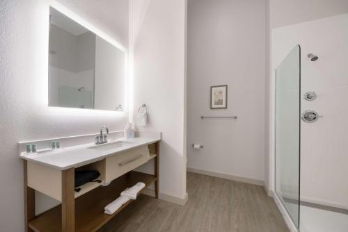 ein Bad mit einem Waschbecken, einem Spiegel und einer Dusche in der Unterkunft Best Western Bandera Suites & Saloon in Bandera