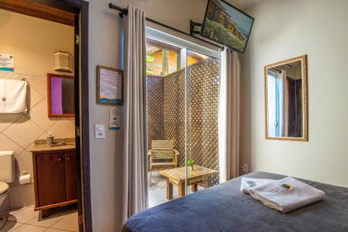 a bedroom with a bed and a door to a bathroom at Pousada Flor de Lotus in Praia do Rosa