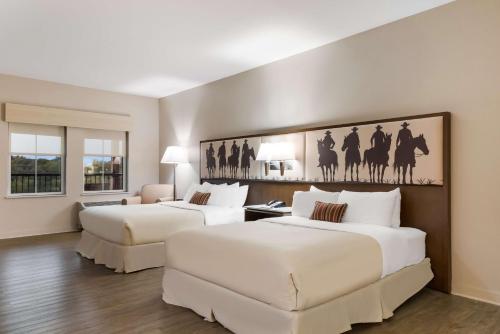 2 Betten in einem Hotelzimmer mit weißen Wänden in der Unterkunft Best Western Bandera Suites & Saloon in Bandera