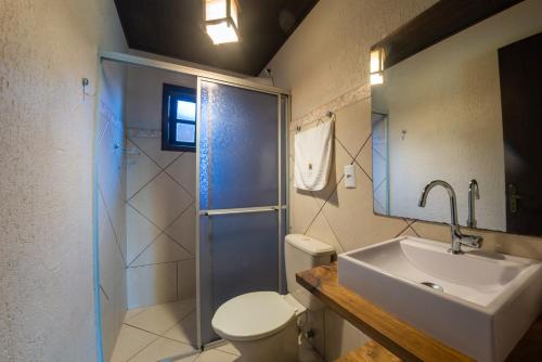 a bathroom with a toilet and a sink and a shower at Pousada Flor de Lotus in Praia do Rosa
