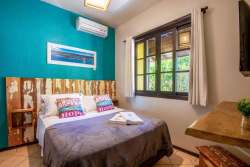 a bedroom with a bed with blue walls and a window at Pousada Flor de Lotus in Praia do Rosa