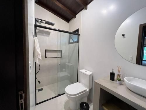 a bathroom with a shower and a toilet and a sink at Pousada Flor de Lotus in Praia do Rosa
