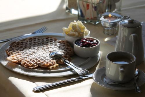 a table with a plate of waffles and a cup of coffee at Waldhotel Dornröschenshöh in Hemfurth-Edersee
