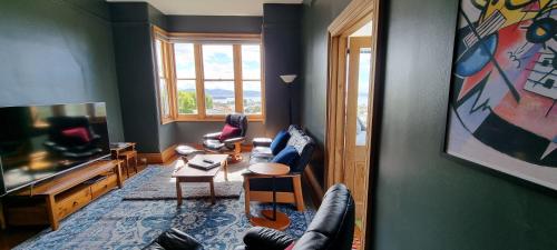 sala de estar con sofá y TV en Hill House Hobart - Charming home, stunning views close to city en Hobart
