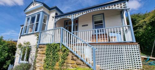 a house with a blue railing on the stairs at Hill House Hobart - Charming home, stunning views close to city in Hobart