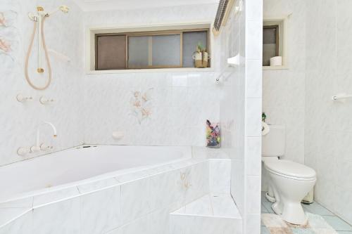 un bagno bianco con vasca e WC di Baywatch Waterfront Lake Retreat with Private Jetty at Silverwater Lake Macqaurie a Bonnells Bay