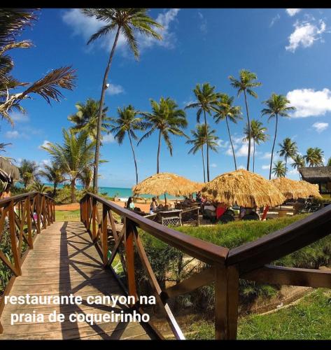 a wooden boardwalk leading to a beach with palm trees at Flat Tabatinga Nord, vista para o mar in Conde