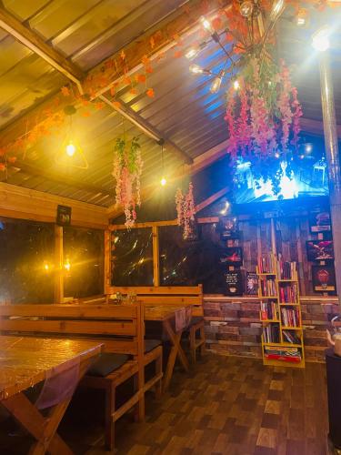 a dining room with wooden benches and a chandelier at Mystic Vibes - Jibhi in Jibhi