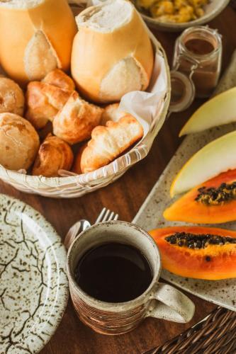 Una mesa cubierta con cestas de pan y una taza de café. en Pousada Medeiros, en Monte Verde