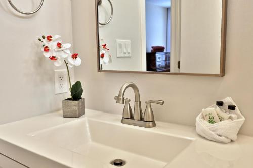 a bathroom sink with a mirror and a vase of flowers at Skiers! Fox Hollow 2BR 2BA Condo, Across from Pico, Minutes to Killington condo in Mendon
