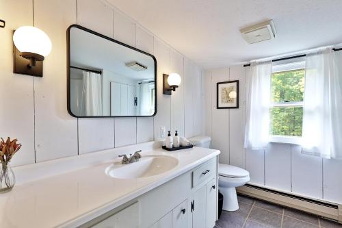 a white bathroom with a sink and a mirror at Forest Mountain Escape- Beautiful Mountaintop Escape in Mendon, VT, 20 min to Killington 14 to Pico, home in Mendon