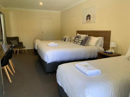a hotel room with two beds and a desk at Mudgee Vineyard Motor Inn in Mudgee