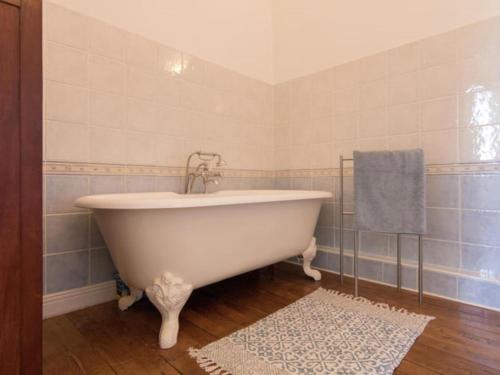 La salle de bains est pourvue d'une baignoire blanche et d'un tapis. dans l'établissement Le Petit Chateau, à Brouchaud