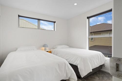 two beds in a white bedroom with a window at Addington Delight - Christchurch Holiday Home in Christchurch