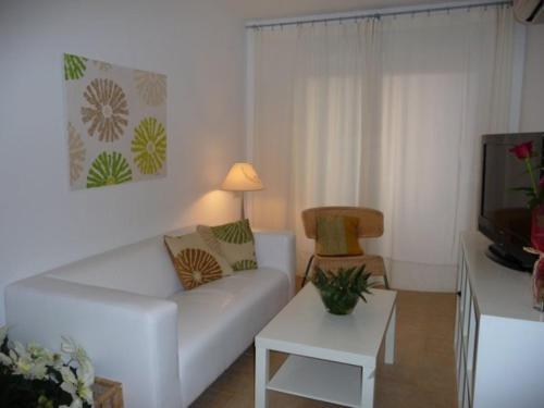 a living room with a white couch and a tv at Apartamentos Playa de Moncofa in Moncófar