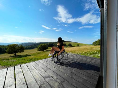 una mujer montando una bicicleta en un porche en Prosportówek - Sierpnica - Domek w Górach z Pięknym Widokiem, en Sierpnica