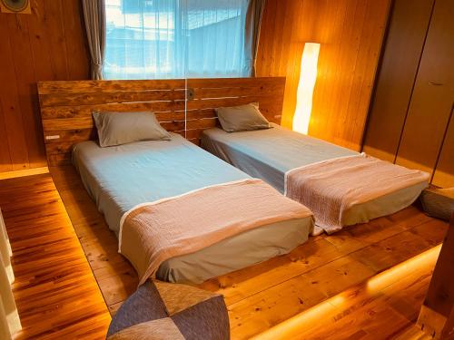Dos camas en una habitación con suelo de madera. en 奄美 大和宿 AMAMI yamato INN, 