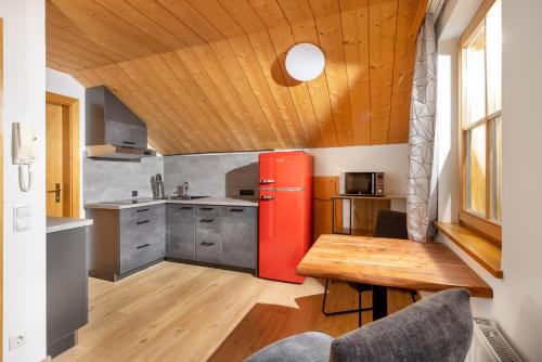 a kitchen with a red refrigerator and a wooden ceiling at Apartmenthaus Matri by Pferd auf Wolke in Wald am Arlberg