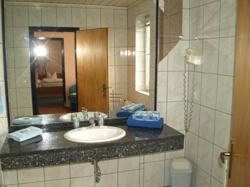 a bathroom with a sink and a mirror at Hotel Ammerland garni in Wilhelmshaven
