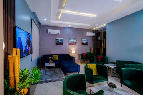 a living room with a blue couch and green chairs at Wali's Suites in Abuja
