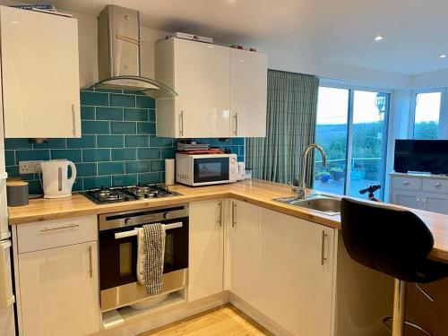 a kitchen with white cabinets and a stove and a sink at Woodside Cabin in Inverness