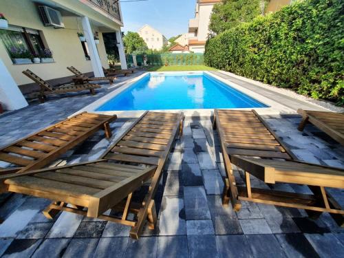 uma piscina com bancos de madeira ao lado de uma casa em Family friendly apartments with a swimming pool Kastel Novi, Kastela - 18645 em Kaštela