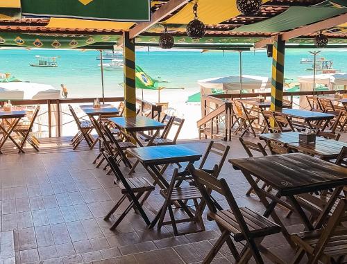 an empty restaurant with tables and chairs and the ocean at Beach Point Barra Grande in Maragogi