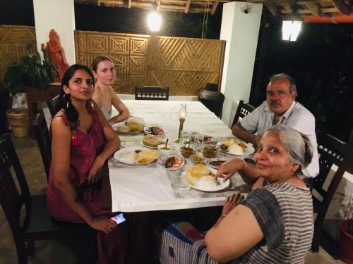a group of people sitting around a table eating food at Vala House - Full Villa in Pallipuram