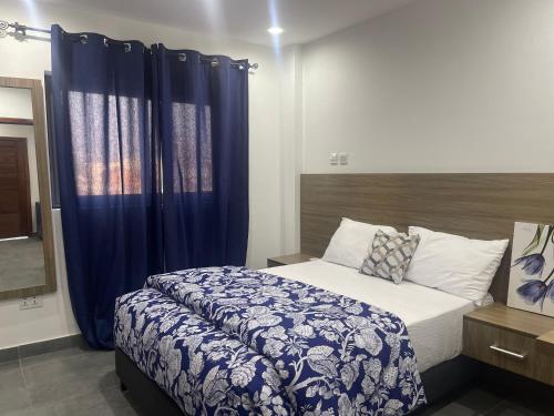 a bedroom with a large bed with blue curtains at Am apartment in Accra