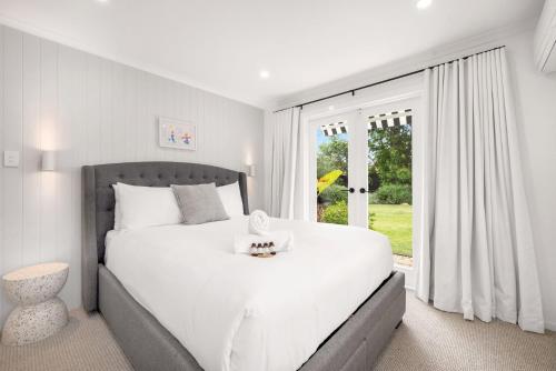 a white bedroom with a large bed and a window at Serenity by the Sea in Scarborough