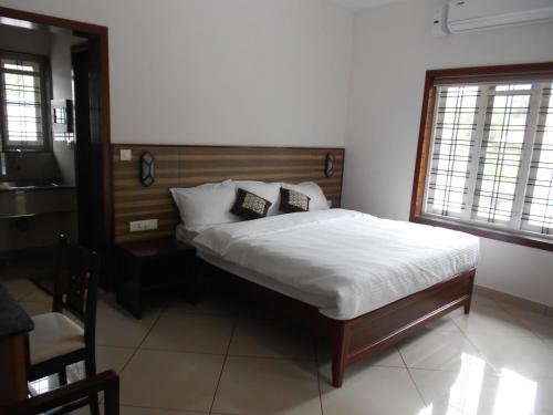 1 dormitorio con 1 cama con sábanas y almohadas blancas en EV StayZ, en Cherai Beach