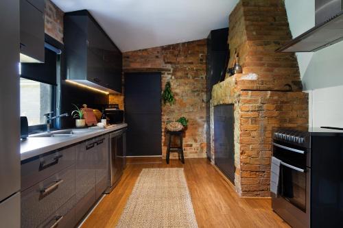 a kitchen with black cabinets and a brick wall at The Nook in Daylesford