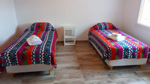 two beds sitting next to each other in a room at Apart Azul Calafate in El Calafate