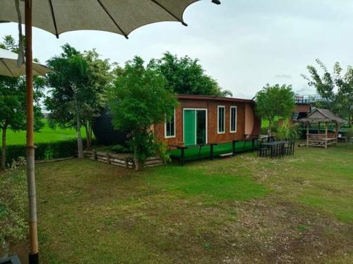 a small house in a yard with an umbrella at บวกบัววิวรีสอทร์ in Nan