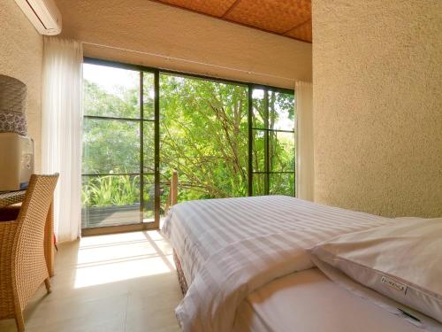 1 dormitorio con cama y ventana grande en Thalassa Dive & Wellbeing Resort Manado, en Manado