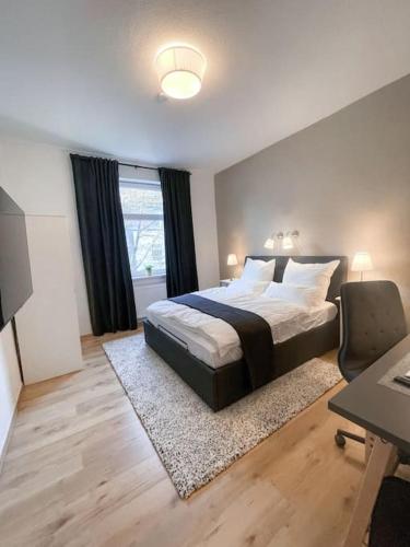 - une chambre avec un grand lit, un bureau et une table dans l'établissement Modern Cozy apt. -with 2 TV, Netflix and work desk, à Essen