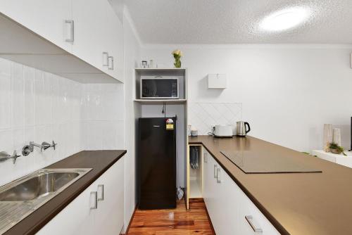 a kitchen with a black refrigerator and a sink at Allamanda Unit 22 in Long Jetty