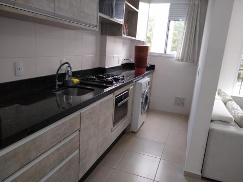 a kitchen with a sink and a stove at Condomínio Ilha do Sol in Florianópolis