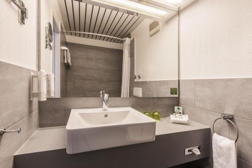 a bathroom with a sink and a mirror at Holiday Inn Düsseldorf-Neuss by IHG in Neuss